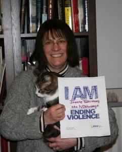 Picture of Joanne Tosti-Vasey standing with sign that says "I AM Ending Violence"