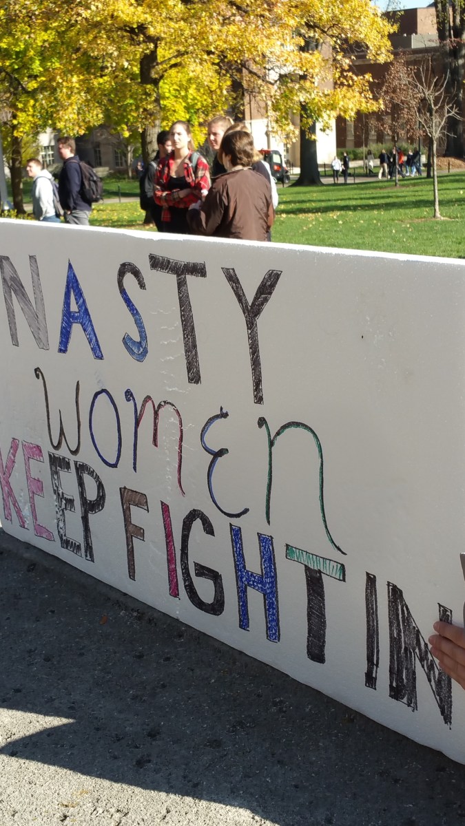 Large fiberboard sign saying "Nasty Women Keep Fighting."