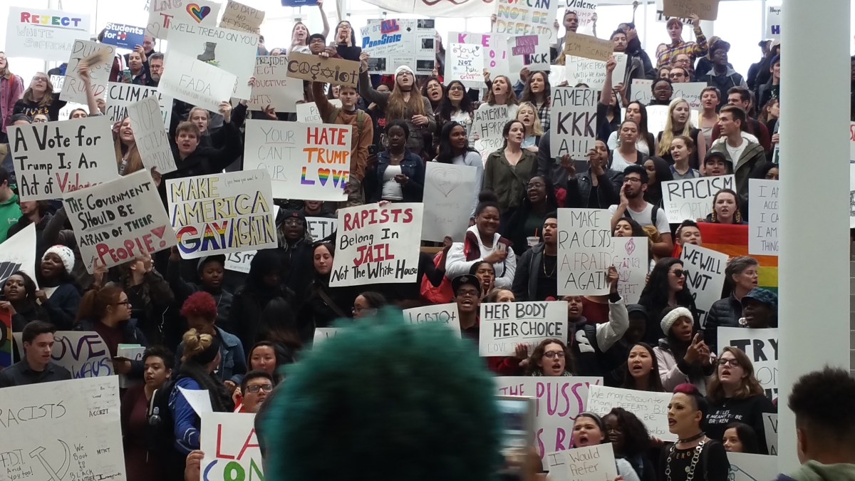 picture of signs and people standing on the steps leading up to the Paul Robeson Cultural Center at the HUB on PSU's University Park Campus.