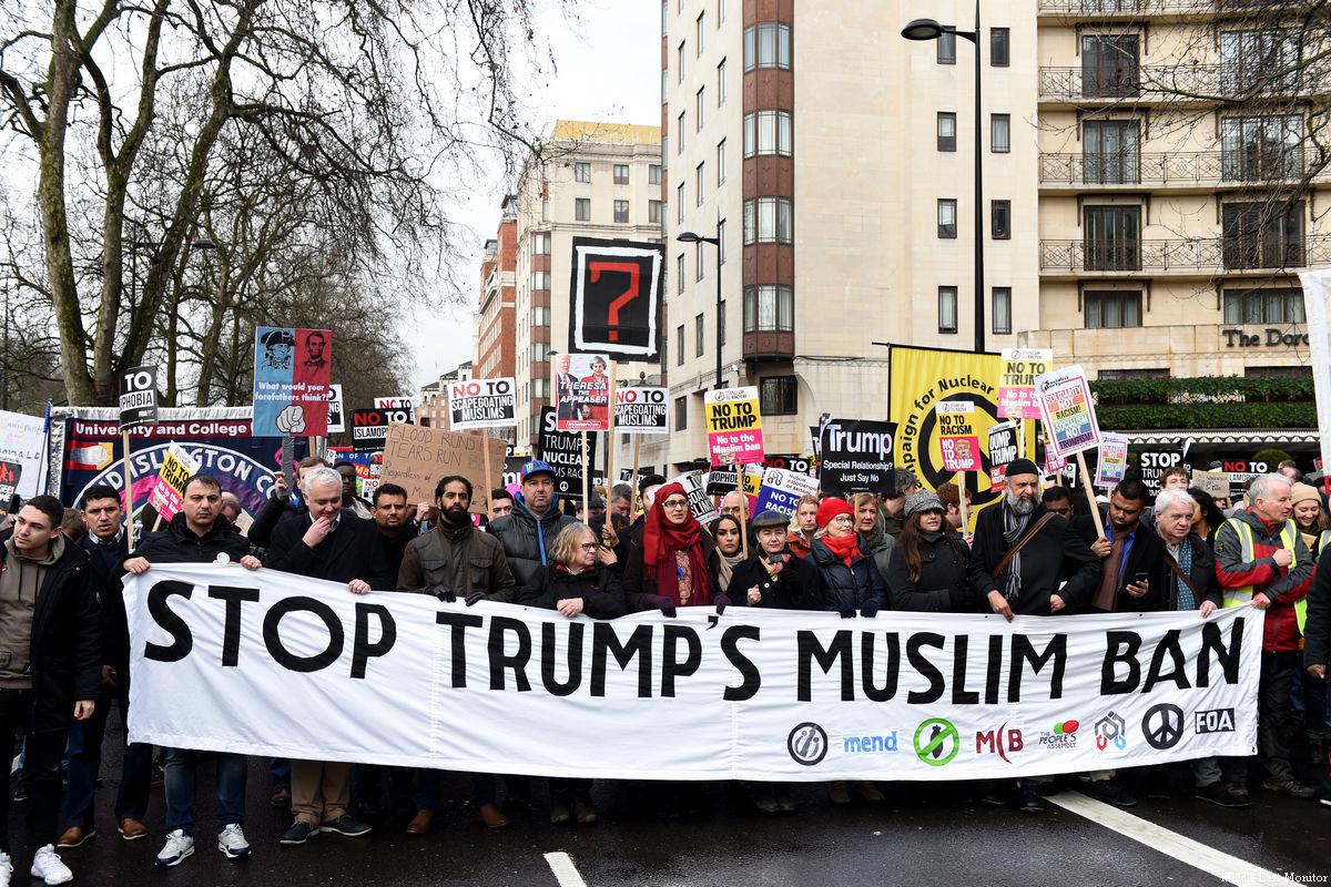 picture of people marching down a city street carrying a banner that says, "Stop Trump's Muslim Ban."